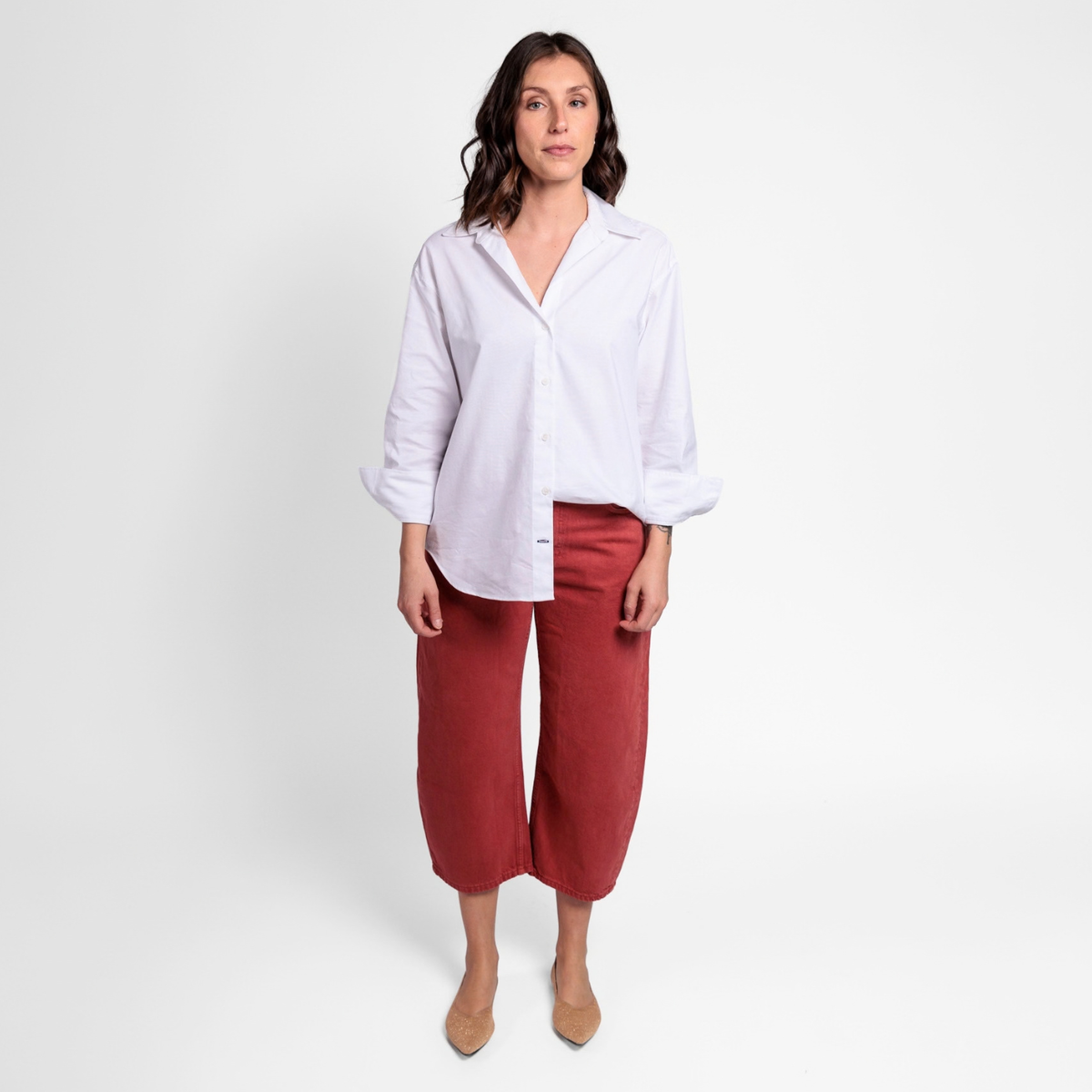 Mujer usando zapatos dorados Superblandas con un look casual de pantalón rojo y camisa blanca